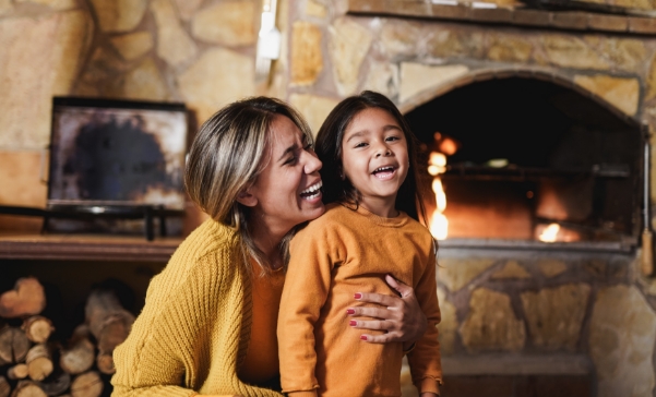 mother-hugging-little-daughter-near-fireplace-smal